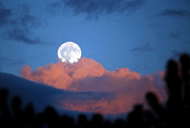 Skyscape photography of a full moon and clouds at dusk.